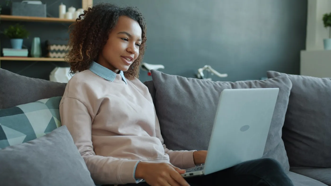 A woman sitting on a sofa at home, using a laptop