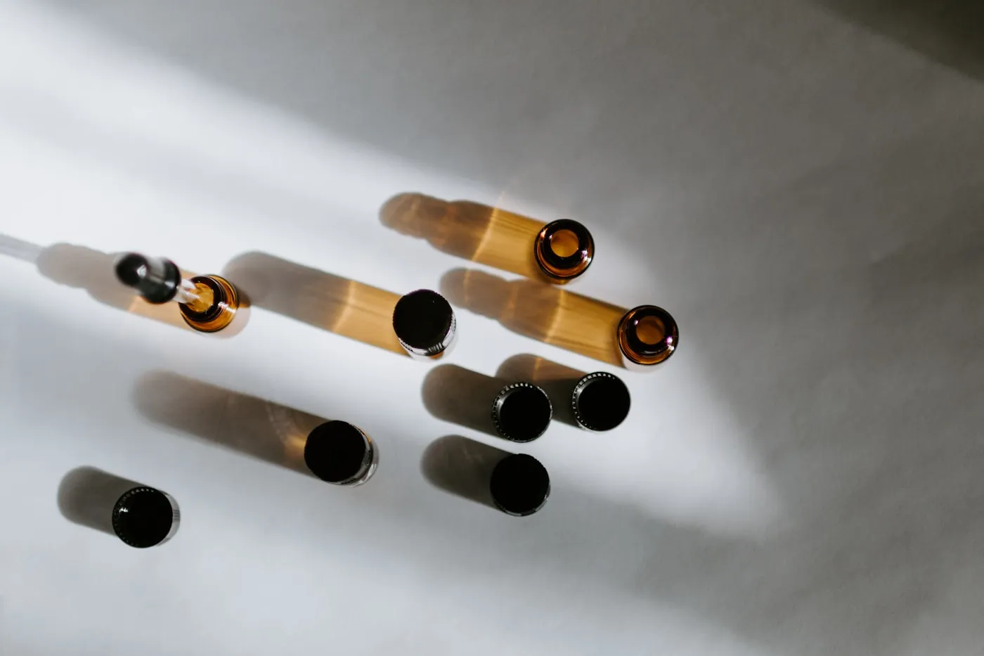 Amber glass vials resting on a white surface in soft daylight