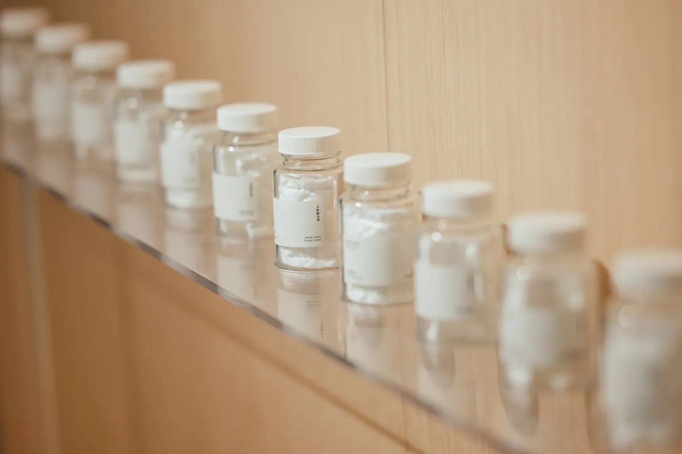 Small unlabelled glass vials with white caps lined up on a shelf